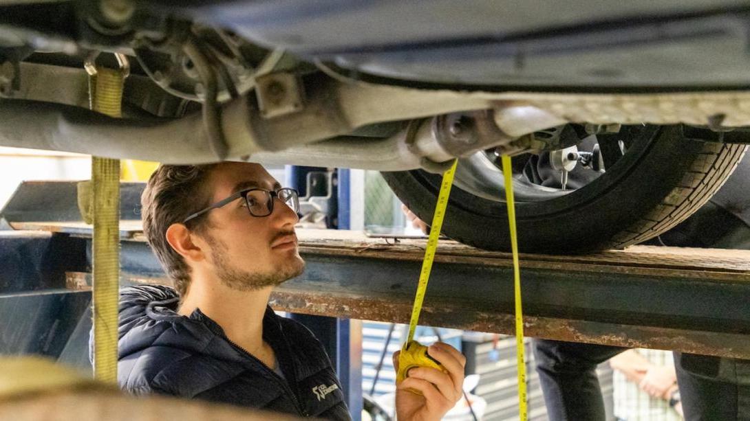 A student working on a car in the SAE garage